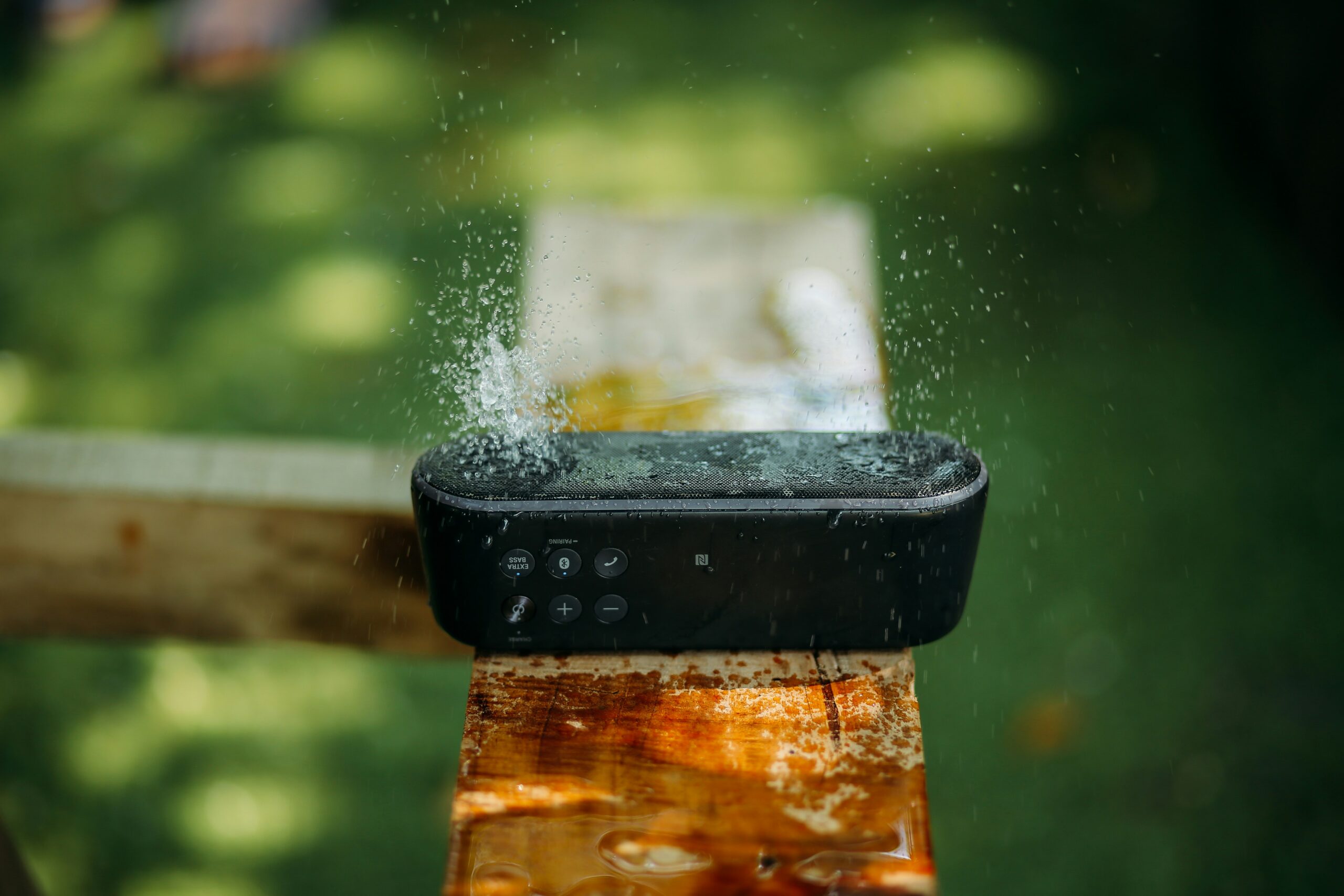 selective focus photography of water resistant oblong black portable Bluetooth speaker on brown lumber